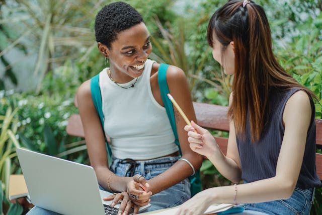 Joyful multiethnic female students working on assignment in park. Photo credit: Zen Chung via Pexels.