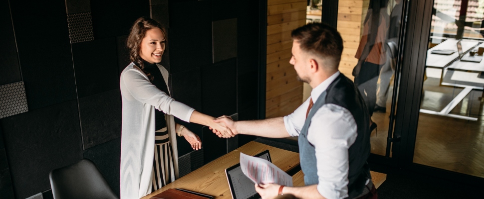 A female and a male professional shaking hands in an office environment