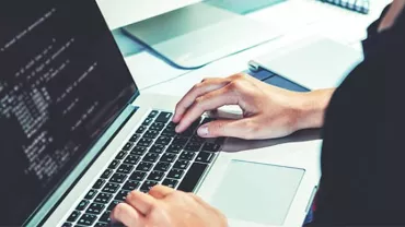 Person typing on a laptop with code displayed on the screen.