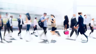 Blurred image of people walking on a busy city street.