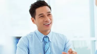 Man in a blue shirt smiling during a meeting.