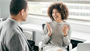 Two colleagues having a cheerful discussion in a modern office.