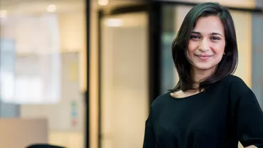 Person smiling in a modern office setting.