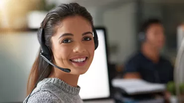 Woman with headset smiling at desk in office