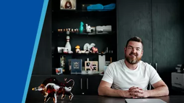 Man sitting at a desk with decorative shelves behind him.