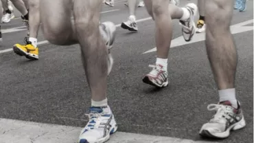 Runners' legs and sneakers on a road during a race.