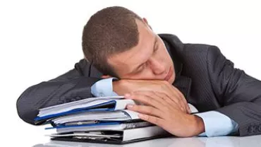 Man in suit sleeping on a pile of documents.