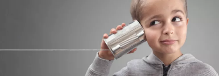 Child listens with a tin can telephone, string pulled taut.