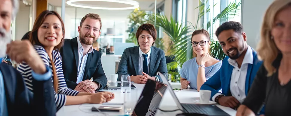 Diverse colleagues in a modern office meeting around a table.